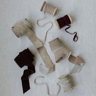 A luxurious arrangement of hand dyed velvet ribbons in various shades, showcasing the artisanal quality of CG Hunter’s Hand Dyed Velvet Ribbon 10 Yards Per Spool – Set of 2 against a soft textured background.