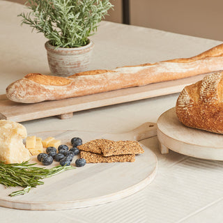 Elegant presentation of the Charlotte Wood Round Serving Board by CG Hunter with assorted cheeses, fresh herbs, and a crusty baguette, ideal for gourmet gatherings.